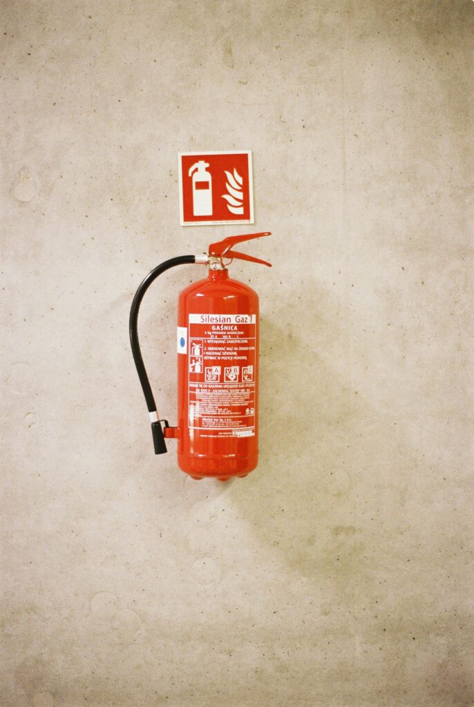 A red fire extinguisher mounted on a concrete wall with safety signage.